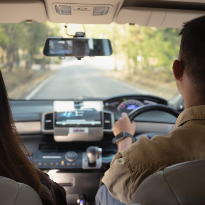 Rear view of couple having fun together driving by countryside. Road trip, traveling and lifestyle concept.